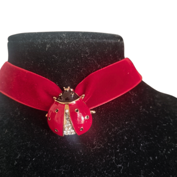 Red velvet ladybug choker with enamel pendant and crystal detail on black display